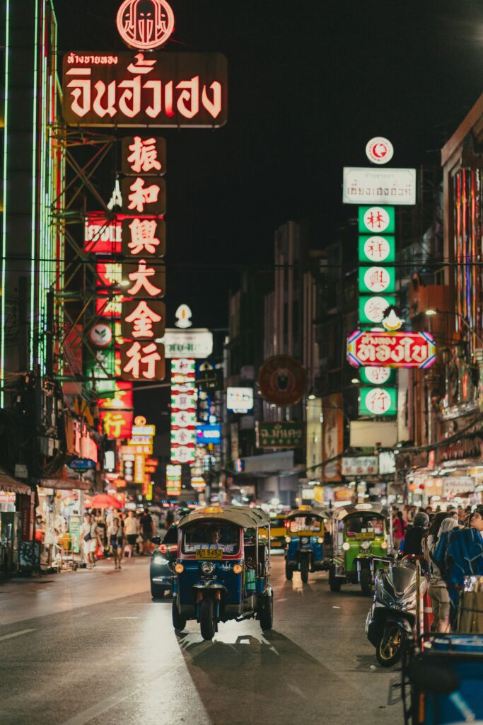 Rue animée de Chinatown Bangkok, illuminée par les enseignes chinoises de Yaowarat Road et les tuk-tuks de nuit.