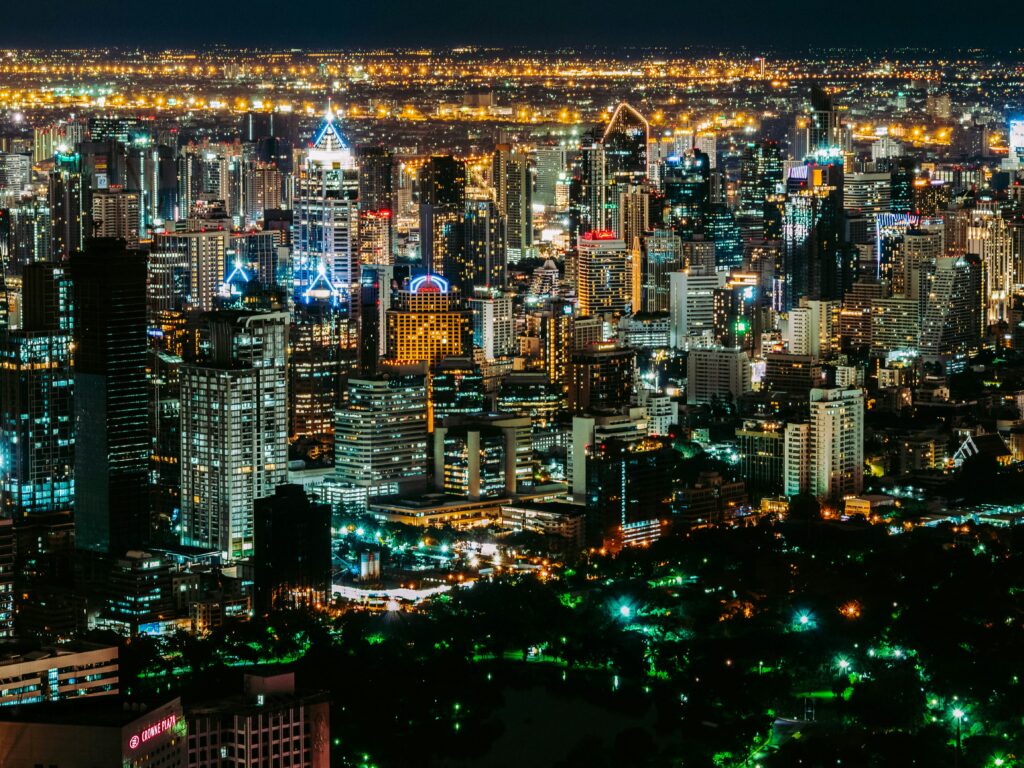 Vue nocturne de Bangkok depuis un rooftop avec les gratte-ciels illuminés — panorama urbain emblématique de la capitale thaïlandaise.