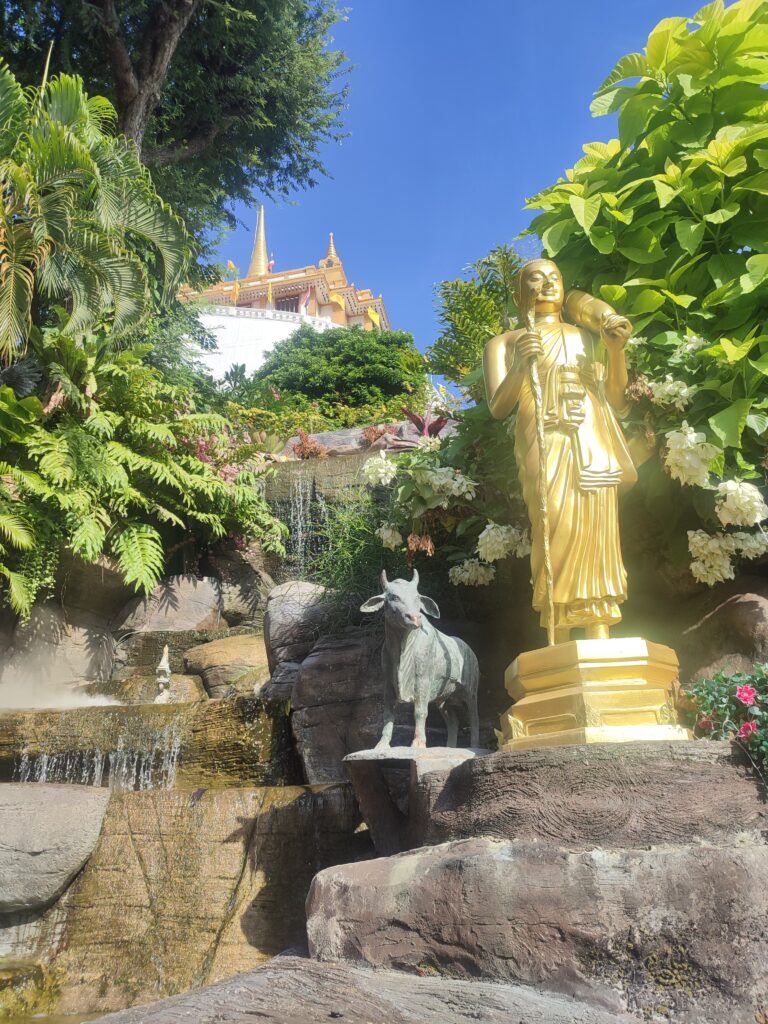 Statue dorée bouddhiste au pied du Wat Saket, avec vue sur le Golden Mount à Bangkok.
